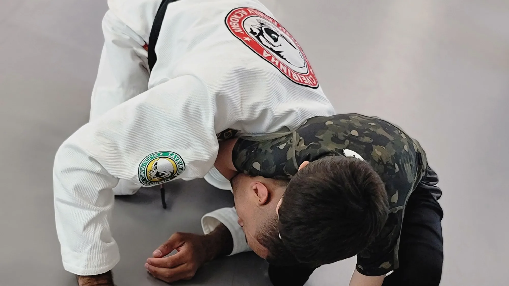 Coach guiding a student through a training position on the CJJF mat